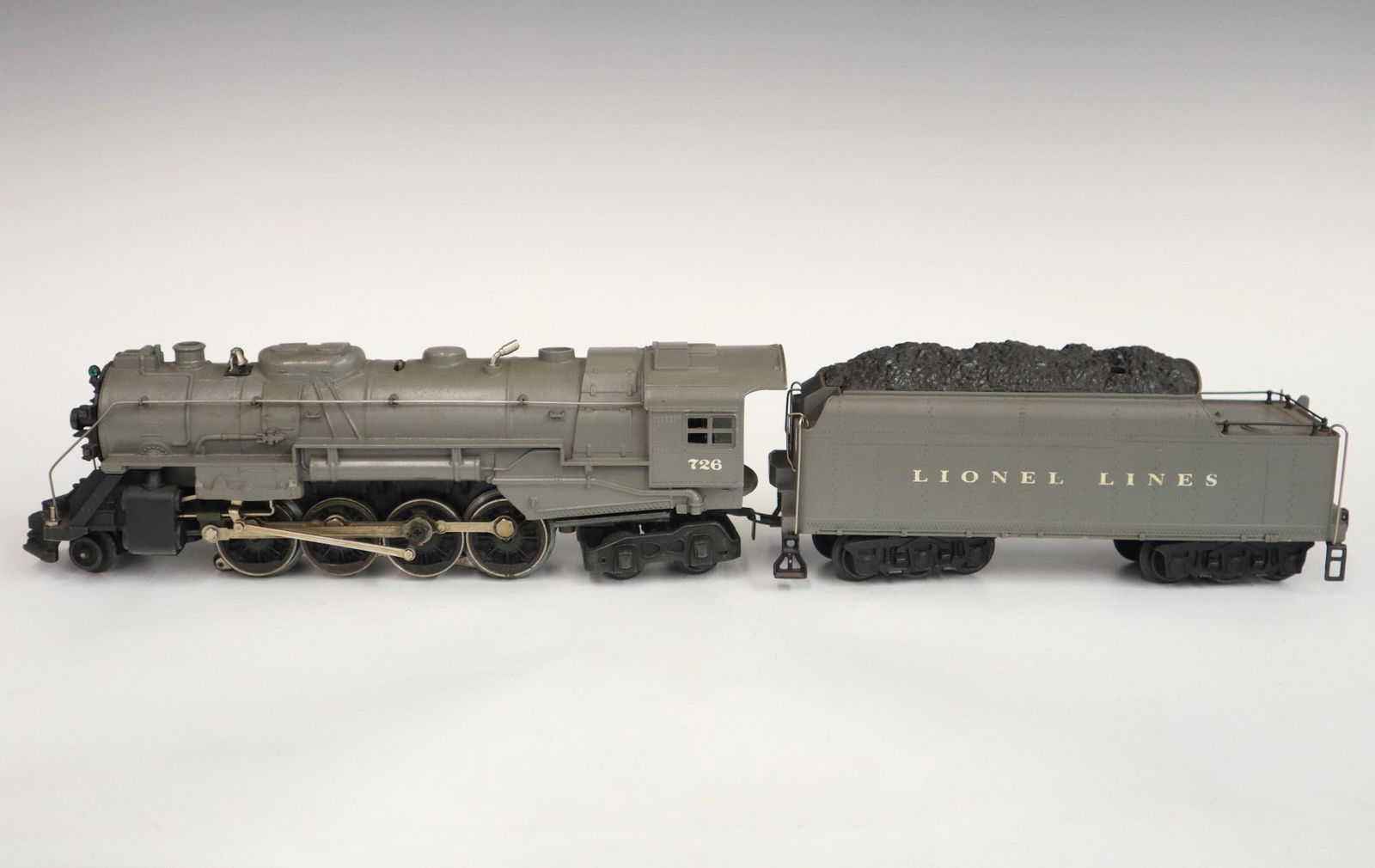 Lionel Locomotive and Tender: A Post-War Lionel O Gauge Locomotive #726 with Original Tender. Grey. Minor wear and soiling. 20" long overall. ESTIMATE $50-100