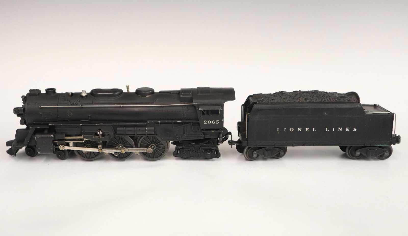 Lionel Locomotive and Tender: A Post-War Lionel O Gauge Locomotive #2065 with Original Tender. Minor wear and soiling. 18" long overall. ESTIMATE $50-100