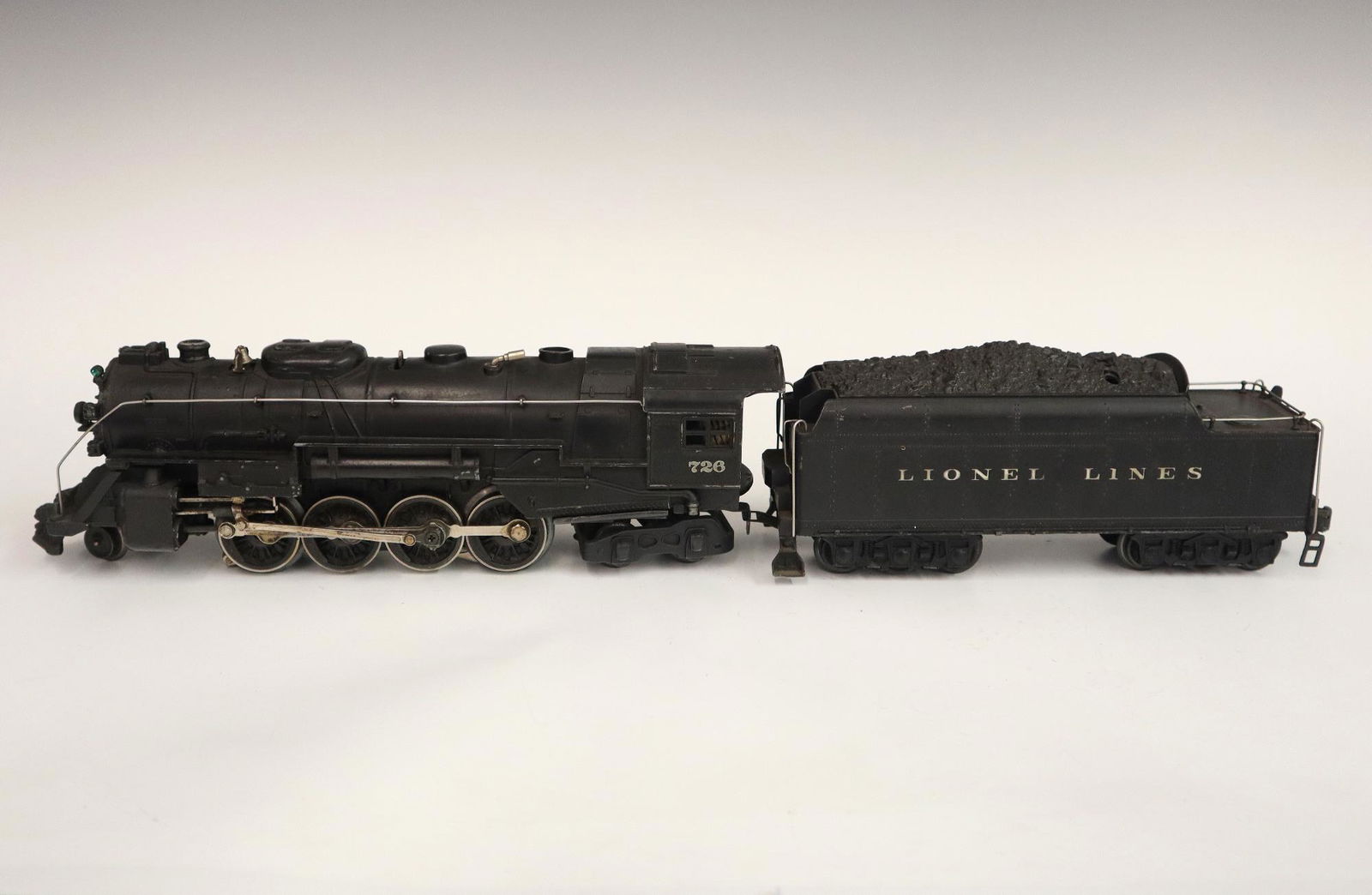 Lionel Locomotive and Tender: A Post-War Lionel O Gauge Locomotive #726 with Original Tender. Minor wear and soiling. 20" long. ESTIMATE $50-100