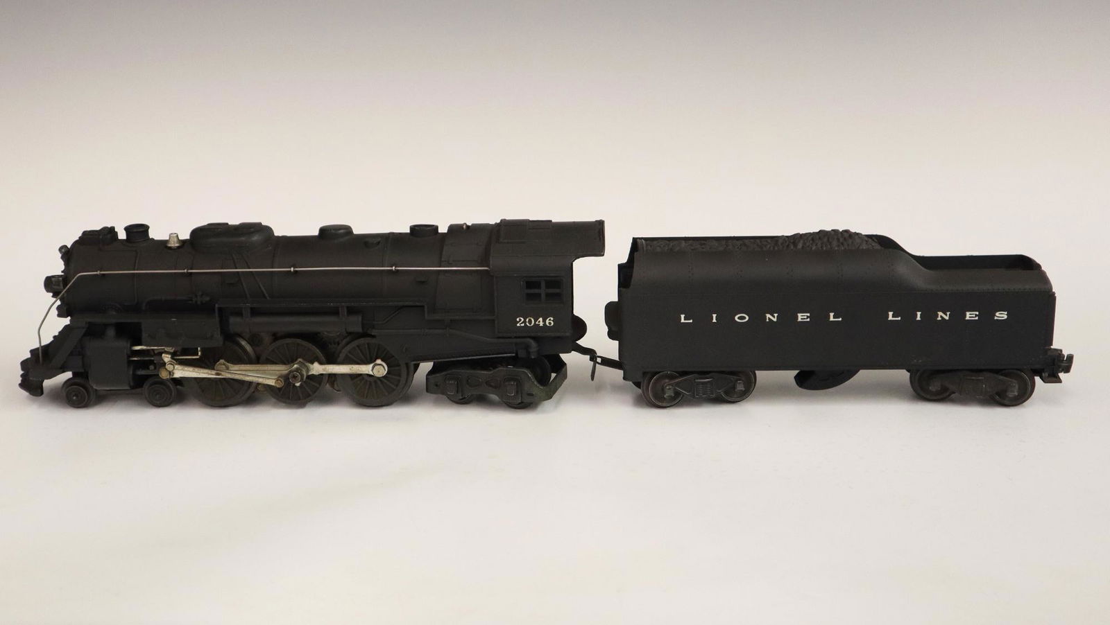 Lionel Locomotive and Tender: A Post-War Lionel O Gauge Locomotive #2046 with Original Tender. Minor wear and soiling. 20" long overall. ESTIMATE $50-100