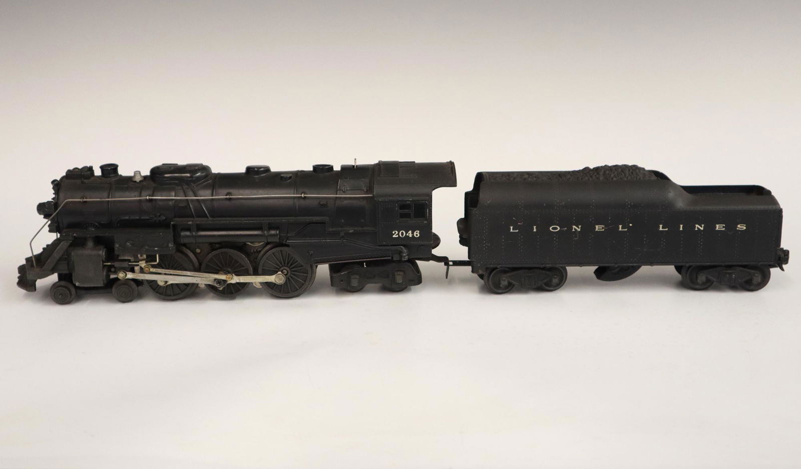 Lionel Locomotive and Tender: A Post-War Lionel O Gauge Locomotive #2046 with Tender #2046W. Minor wear and soiling. 20" long overall. ESTIMATE $50-100