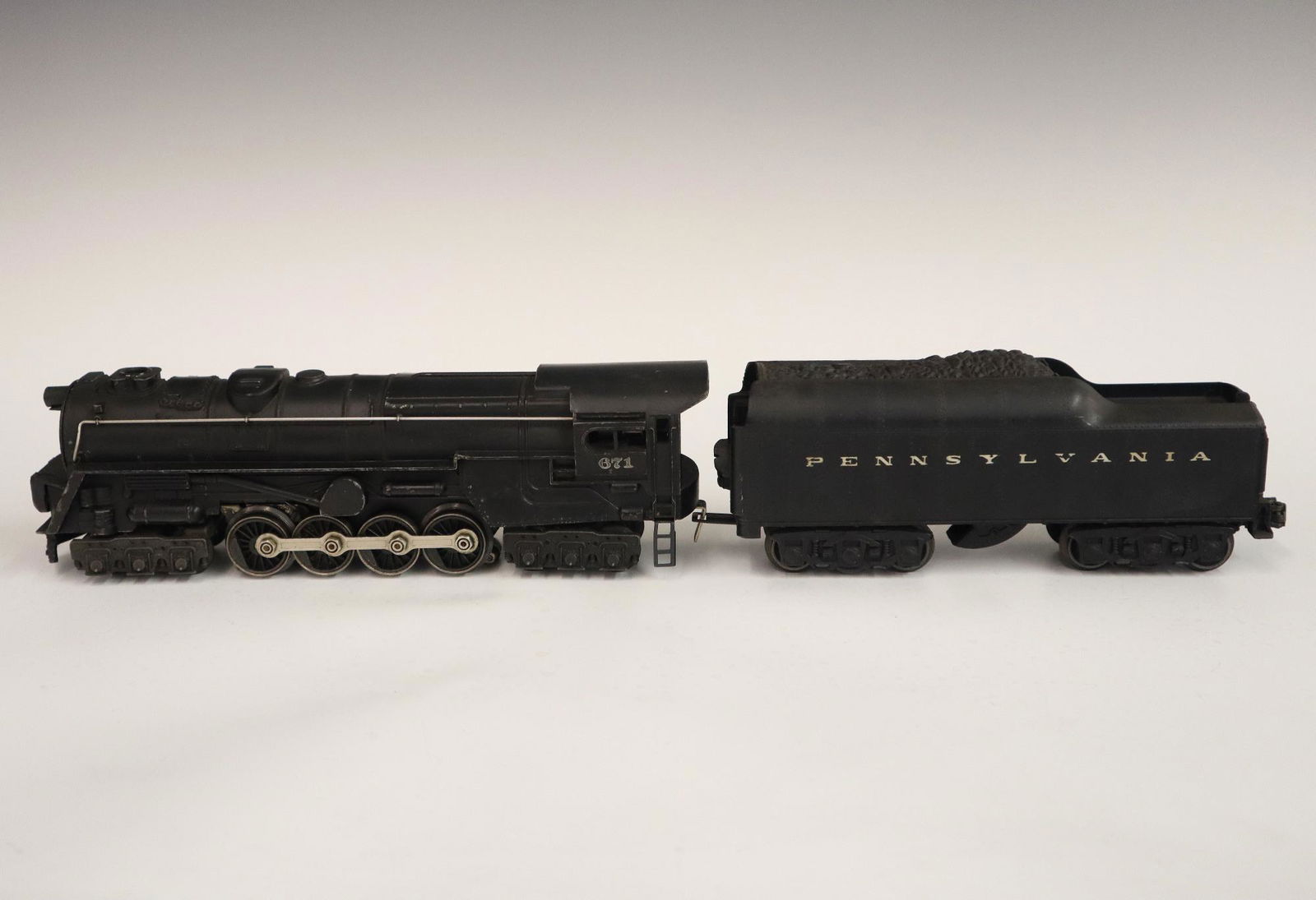 Lionel Locomotive and Tender: A Post-War Lionel O Gauge Locomotive #671 with Tender #2671W. Minor wear and soiling. 19" long overall. ESTIMATE $50-100