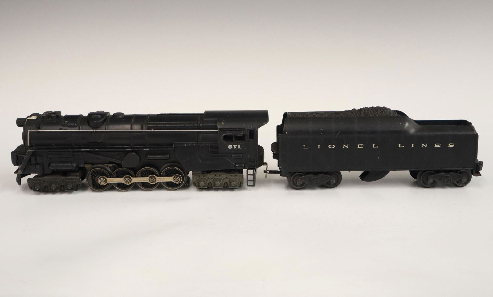 Lionel Locomotive and Tender: A Post-War Lionel O Gauge Locomotive #671 with Tender #2046W. Minor wear and soiling. 19" long overall. ESTIMATE $50-100