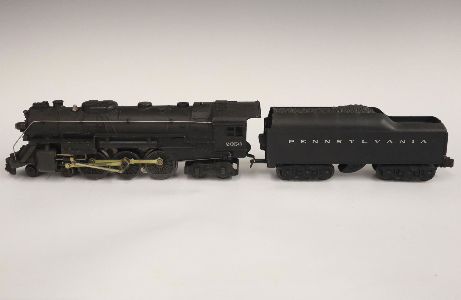 Lionel Locomotive and Tender: A Post-War Lionel O Gauge Locomotive #2056 with Original Tender. Minor wear and soiling. 20" long overall. ESTIMATE $50-100
