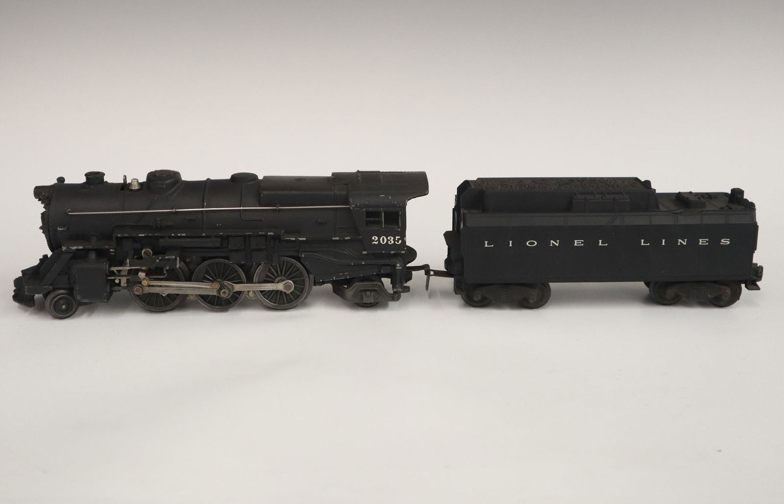 Lionel Locomotive and Tender: A Post-War Lionel O Gauge Locomotive #2035 with Original Tender. Minor wear and soiling. 19 3/4" long overall. ESTIMATE $50-100