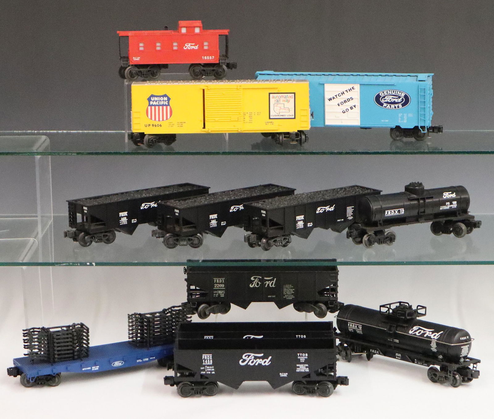 11 Lionel Ford Rolling Stock Cars: Eleven Post-War Lionel O Gauge "Ford" Rolling Stock Cars. Including 1 box car, 2 tankers, 6 hoppers, 1 caboose, and 1 flat car with automotive frames. Minor wear and soiling. Up to 10 1/2" long. ESTIM