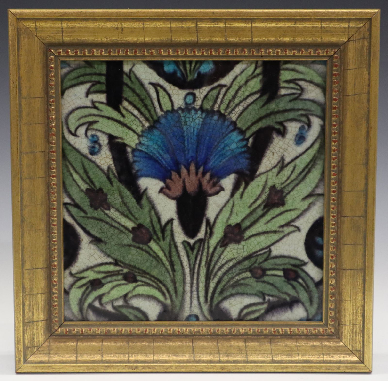 W. De Morgan Tile: A Late 19th Century William De Morgan Art Pottery Tile. Square tile with painted design of blue flower on a field of green leaves, with eggplant colored small floral accents. Impressed "De Morgan Mert
