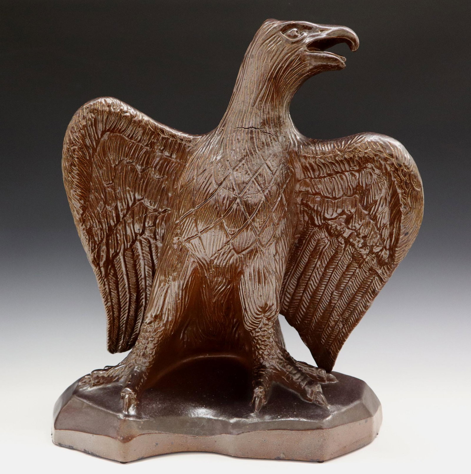 Earthenware Eagle Sculpture: A Late 19th to Early 20th Century Ceramic Sculpture of an Eagle. Depicts an Eagle with its wings spread open, covered with a brown glaze overall. Possibly an architectural or roof ornament. Firing cra