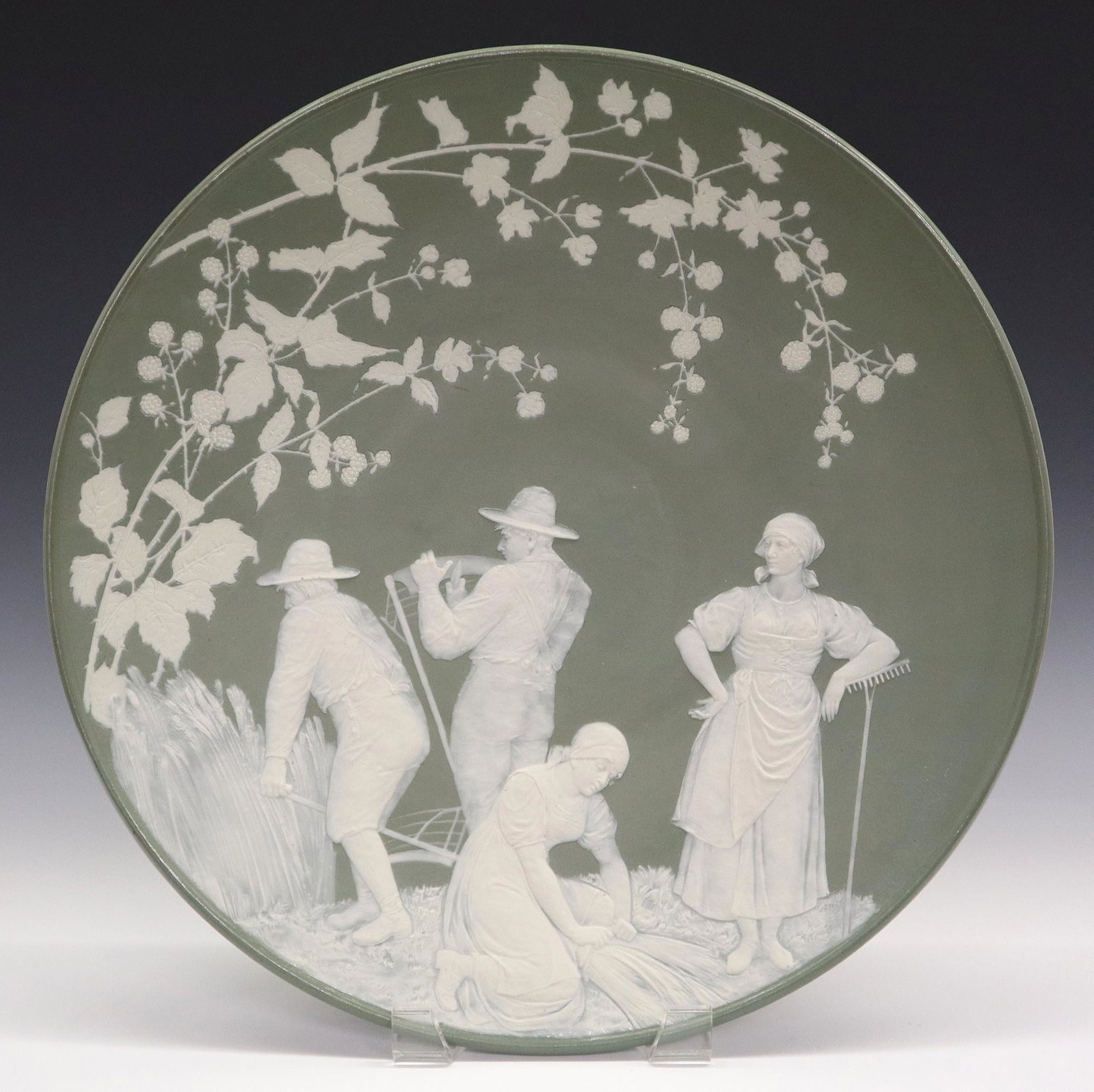 Mettlach Cameo Plaque: A 20th century Mettlach Cameo plaque. #7036 Harvest scene with White figures on a medium Green ground. Impressed marks. Minor wear, tiny edge flake. 17 1/4" diameter. ESTIMATE $200-400