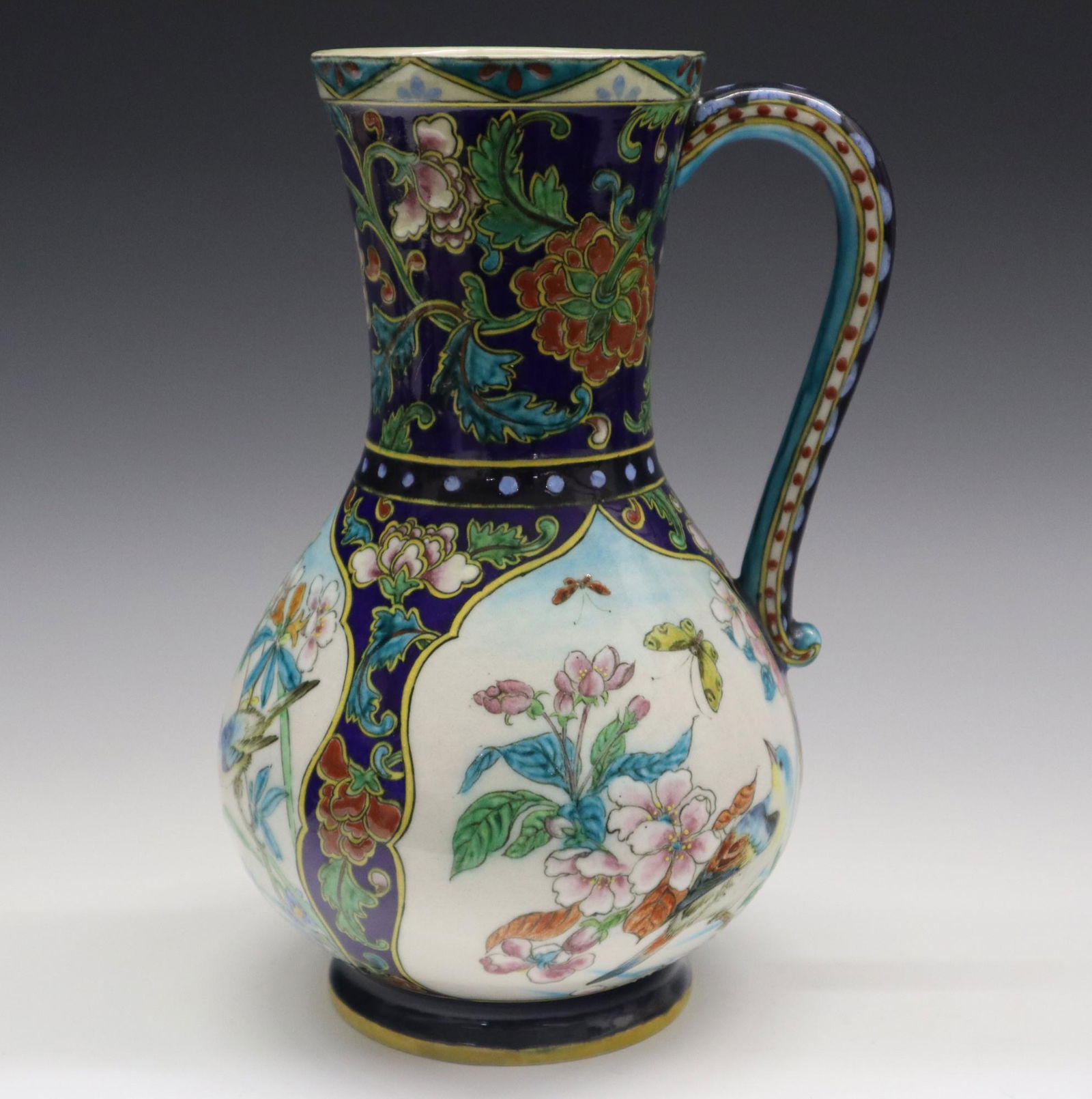 Th. Deck Ewer: A Late 19th Century Theodore Deck Glazed Earthenware Ewer. Multi-color decoration in the Chinoiserie style consists of Chrysanthemums about the neck and between the three vignettes around the body whi