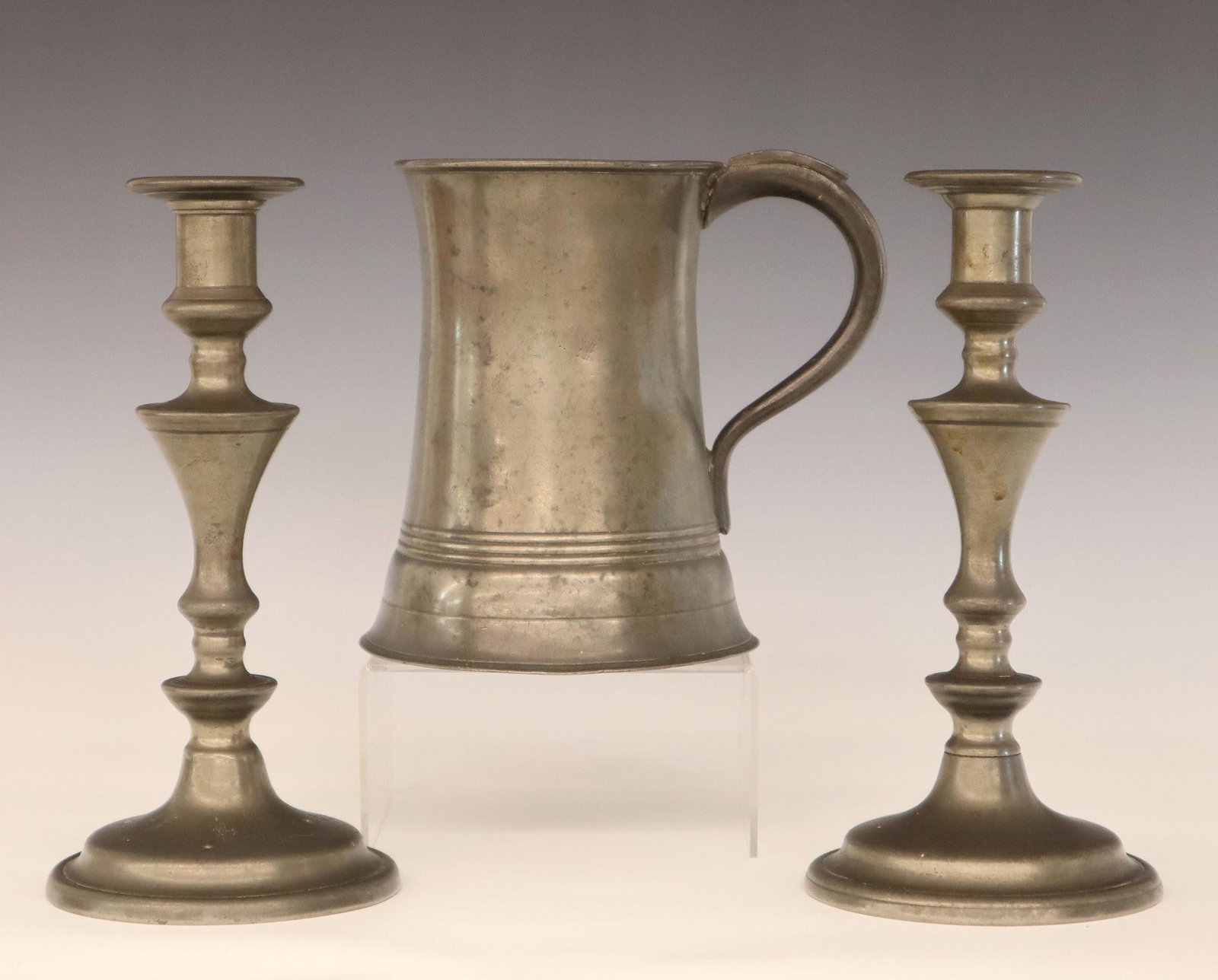 Pewter Candlesticks And Tankard: A pair of 19th century Pewter candlesticks and a quart tankard. Minor wear. Up to 9" high. ESTIMATE $50-75