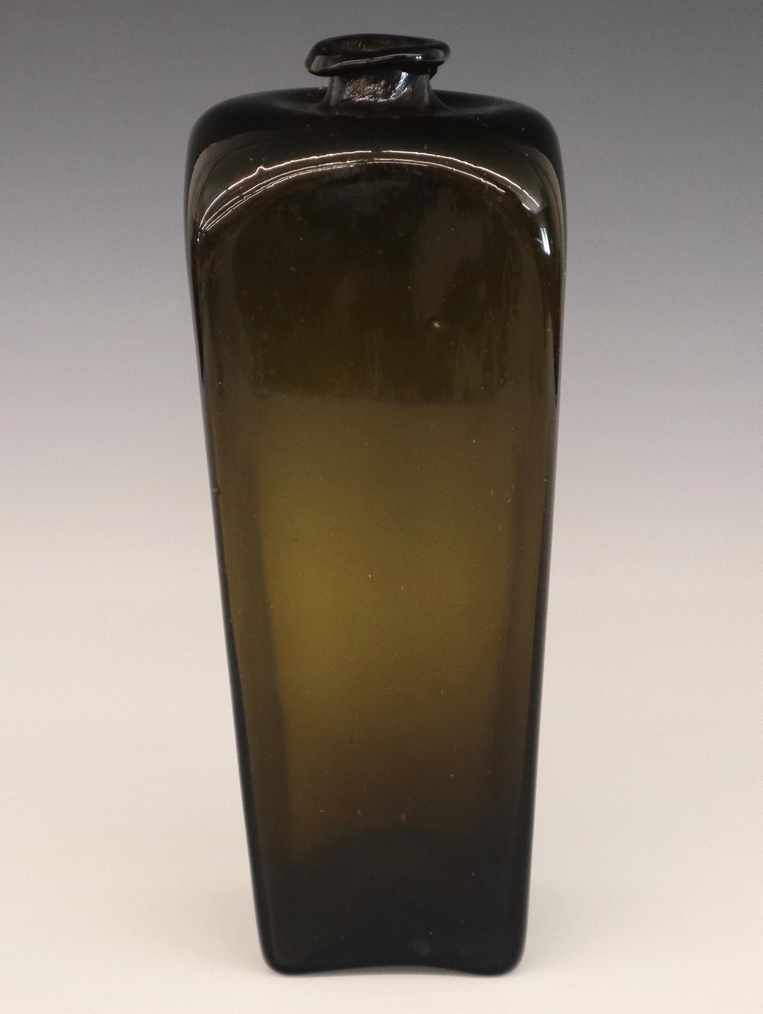 Dutch Case Gin Bottle: An 18th century Dutch case Gin bottle. Blown Olive Green glass with square tapering side and broken pontil. Some wear, rim flakes. 9 1/2" high. ESTIMATE $50-75