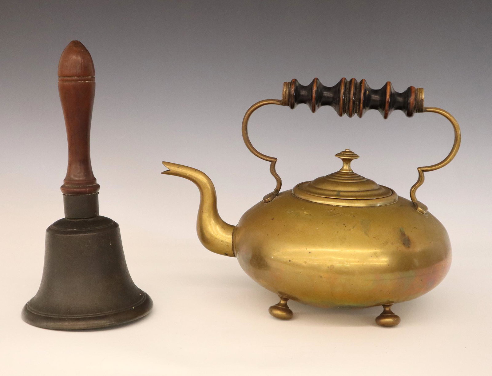 Tea Kettle and School Bell: A mid 19th century brass tea kettle and school bell. Both with turned wooden handles. Some wear and minor denting. Up to 10 1/2" high. ESTIMATE $50-100