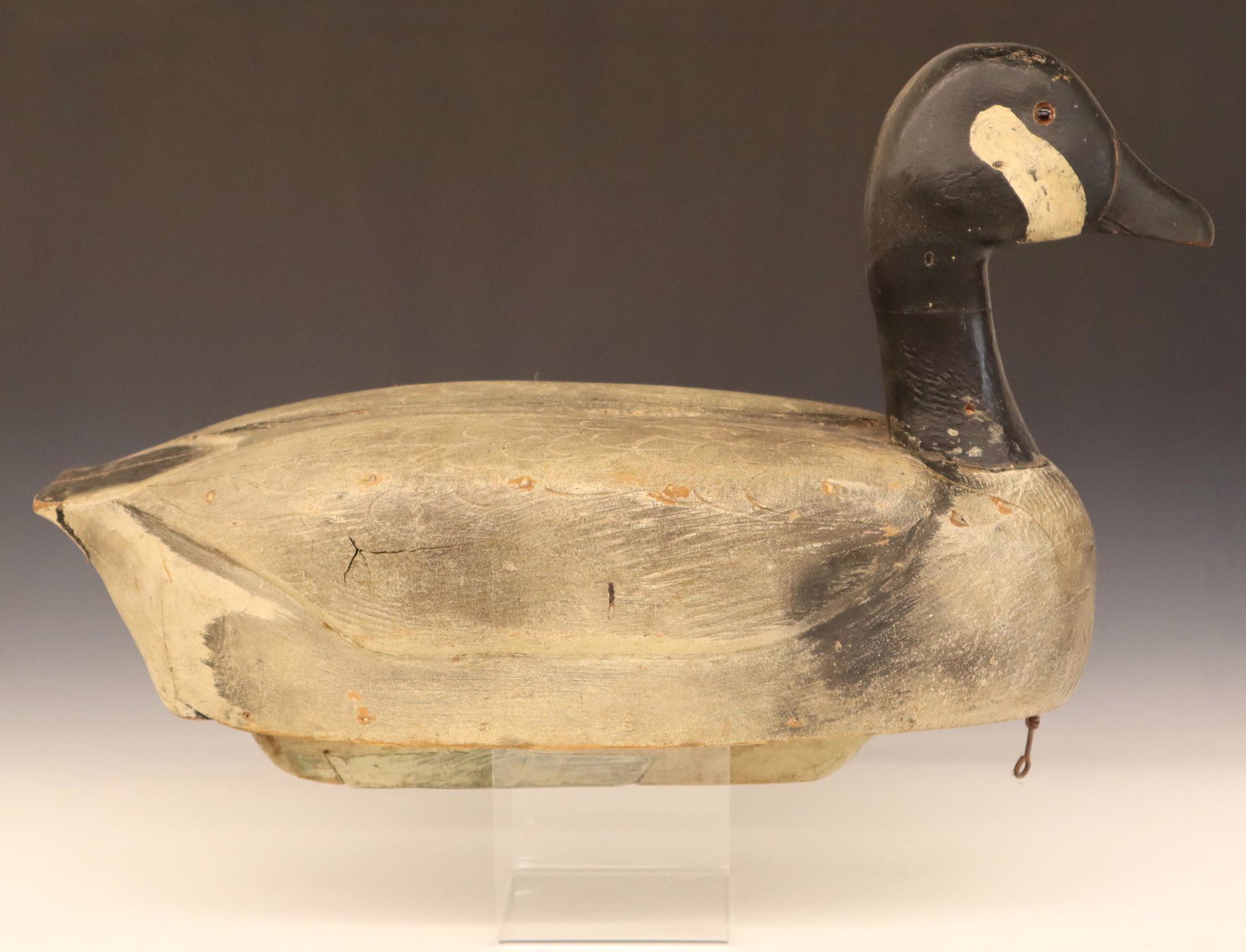 St. Clair Flats Canada Goose Decoy: A 1960's St. Clair Flats Canada Goose Decoy. Carved wooden body with glass eyes and original paint. Wear, some damage, edge chips and loss of some neck filler. 21" long. ESTIMATE $100-200