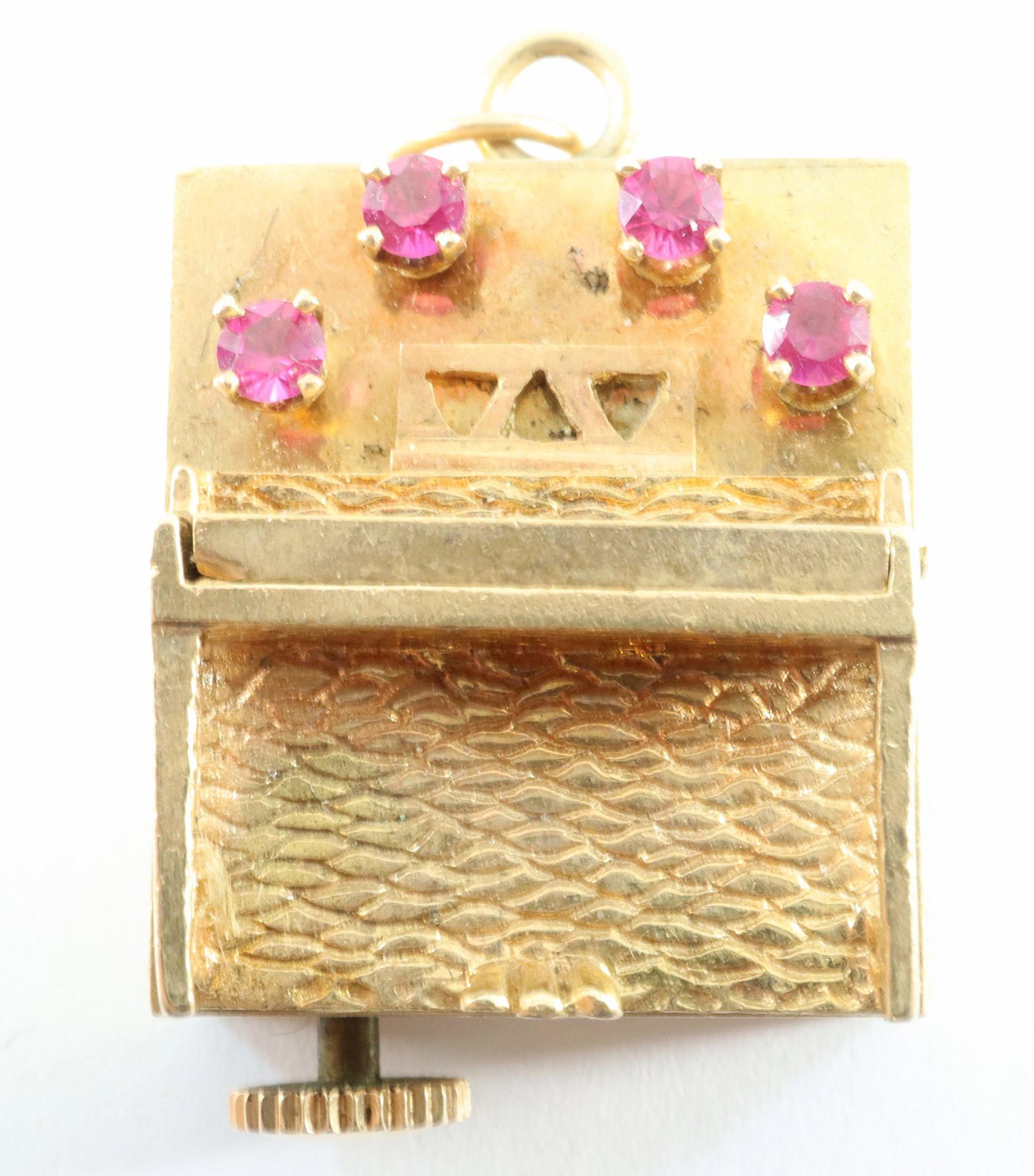 14k Musical Charm with Rubies: A 14k Gold musical charm. Upright piano form body set with four small Rubies. 18.7 grams total weight. Some wear, plays when wound. ESTIMATE $200-400