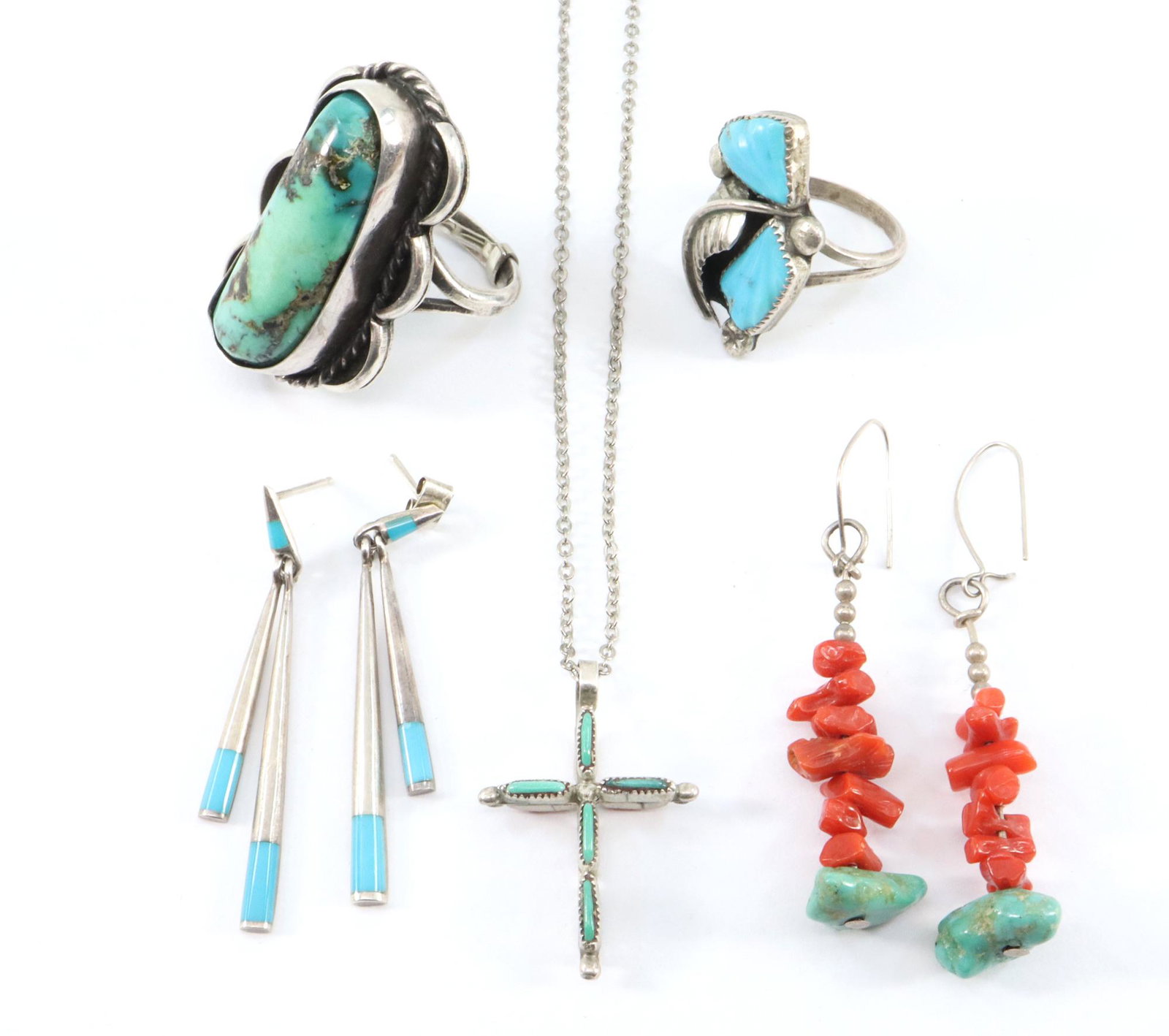 7 pcs Navajo Jewelry: Seven pieces of Navajo Jewelry. Including two Sterling and Turquoise rings, a silver, coral and Turquoise cross and two pairs of drop style earrings. 30.7 grams total weight. Slight wear. Up to 1 1/2"