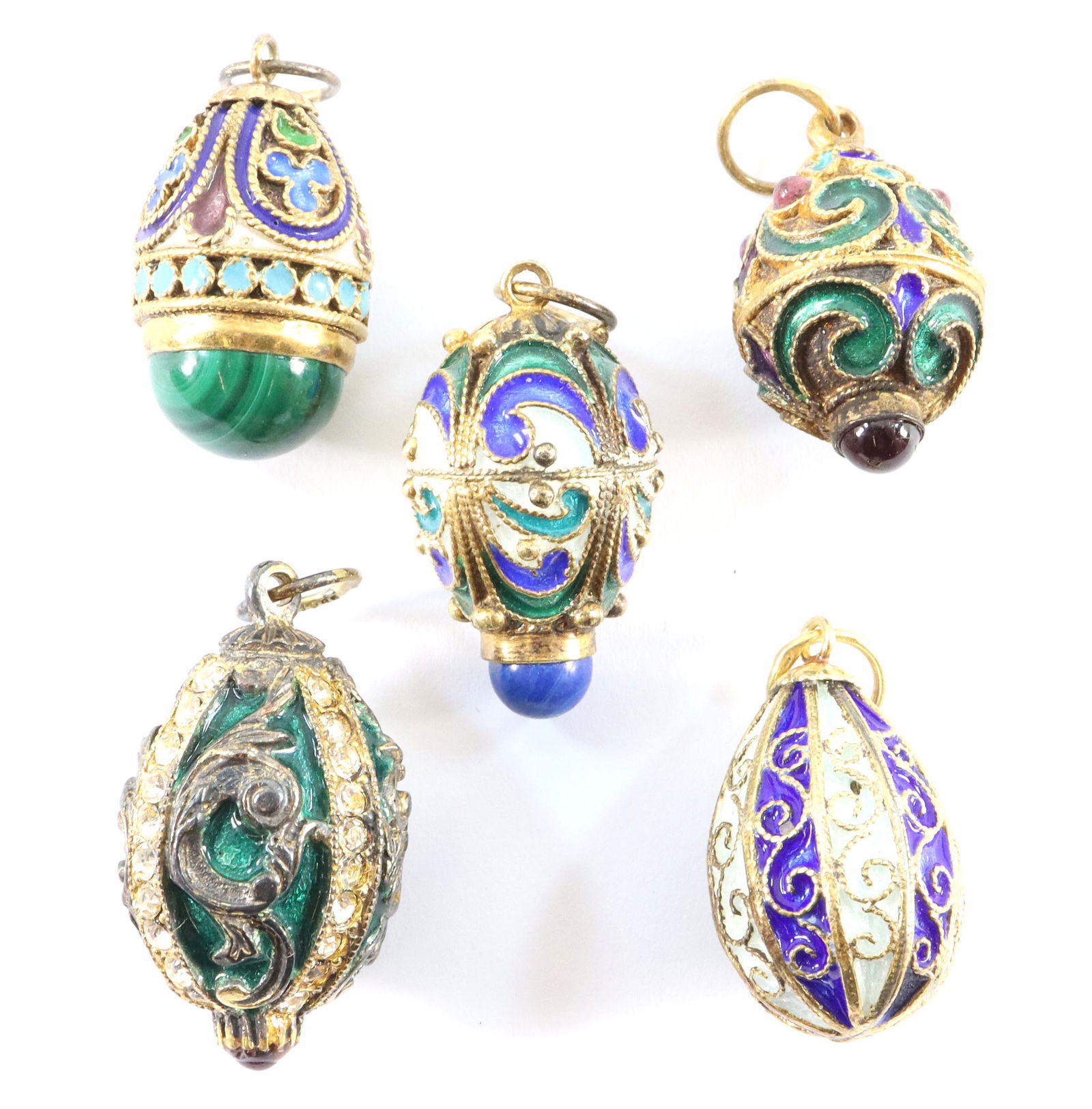 5 Russian Egg Charms: Five Russian egg charms. Champlevé and enamel decoration. Some with "jeweled" detail, one with Malachite insert. Slight wear. ESTIMATE $100-150