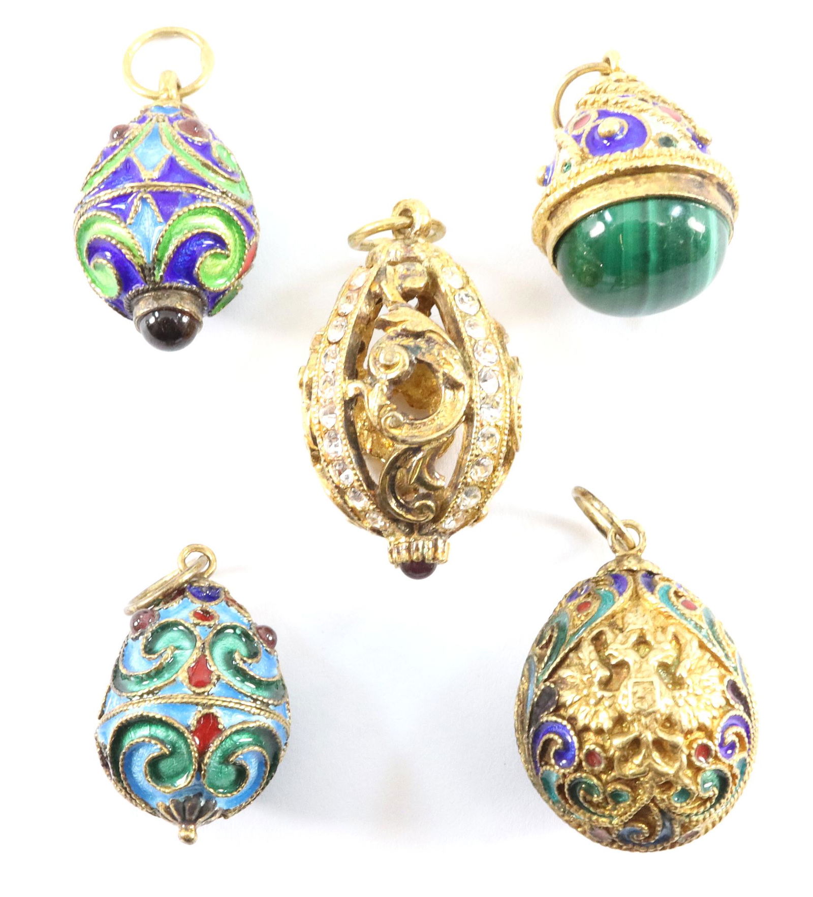 5 Russian Egg Charms: Five Russian egg charms. Champlevé and enamel decoration. Some with "jeweled" detail, one with Malachite insert. Slight wear. ESTIMATE $100-150