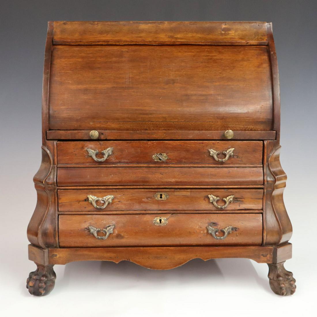 Miniature Cylinder Desk: A 19th century Mahogany Dutch style miniature cylinder roll top desk, roll top opens to reveal fitted interior with five drawers around a center door over a pull out writing surface, all above three d
