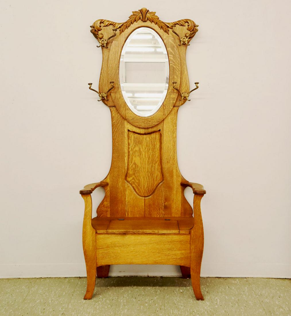 Oak Hall Seat: A turn of the century American Oak Hall Seat, with oval mirror surrounded by four original Iron coat hooks and lift seat storage. In refinished condition, small cloudy spot to mirror. 32 x 14 1/2 x 75