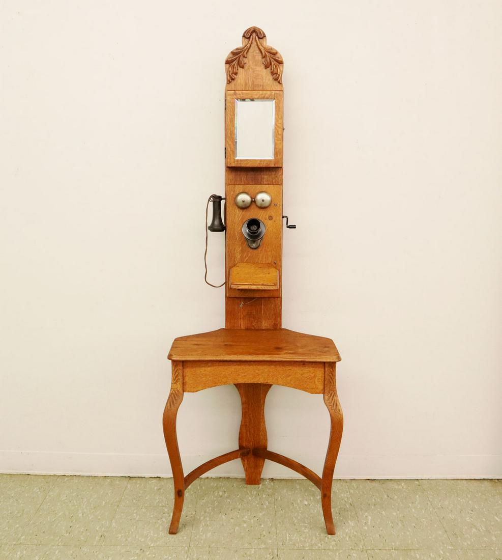 Oak Telephone Stand: A turn of the century American Oak Telephone stand, mirrored storage compartment over a "Kellogg" wall phone above a writing surface. In refinished condition, with some old ink stains to the writing s