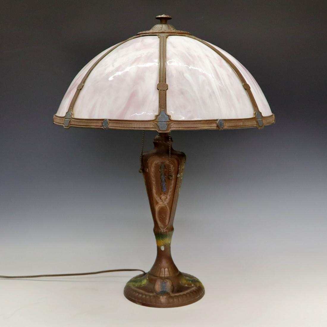 Bent Panel Table Lamp: An early 20th century American bent panel table lamp. Consists of seven rose colored bent glass panels in a spelter frame, on a floral decorated spelter base all with a Copper painted patina. Minor we