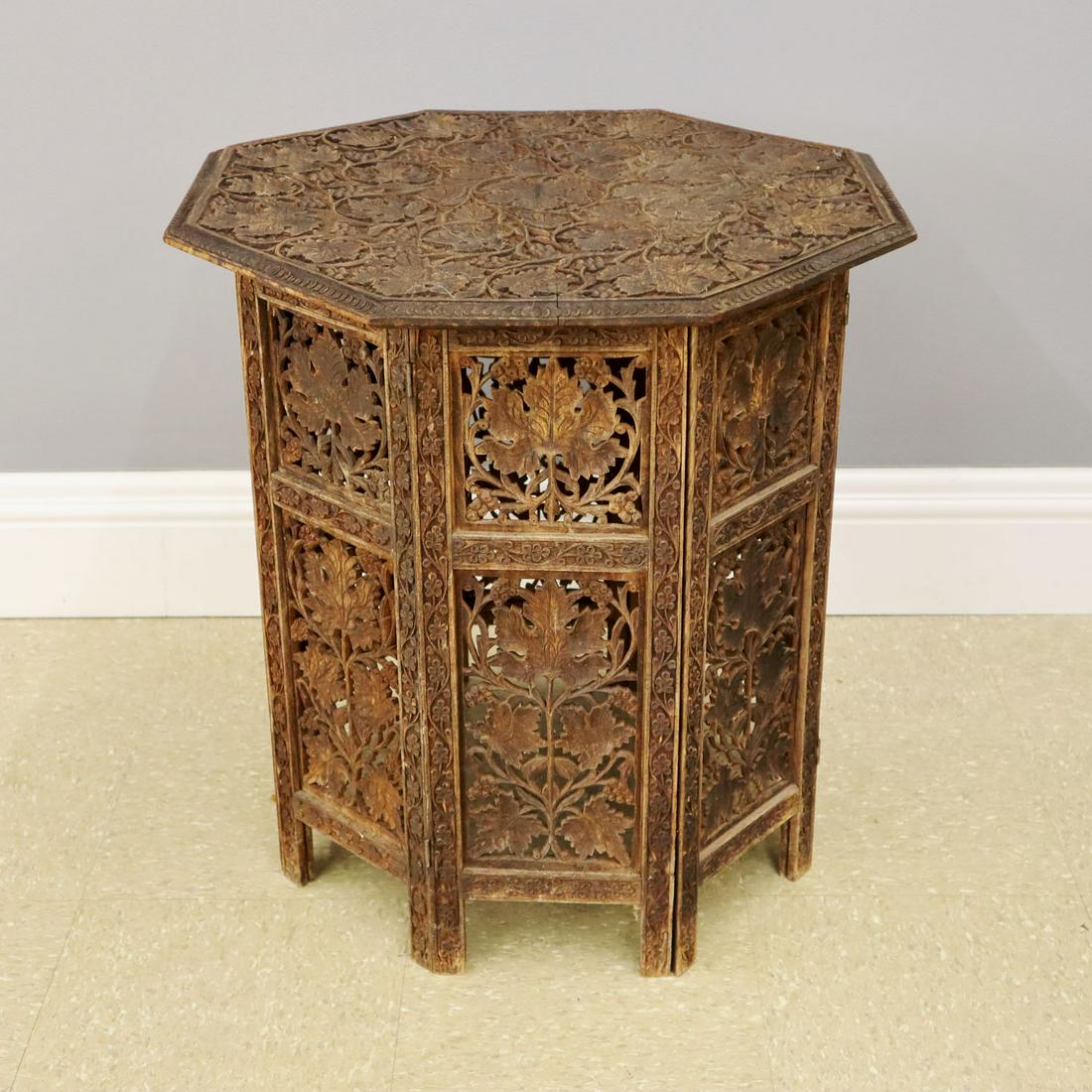 Carved Teak Side Table: An early 20th century Indian carved teak collapsible side table. Old worn finish, minor chips to feet near bottom. 23 1/2 x 24 1/2" high. ESTIMATE $100-200
