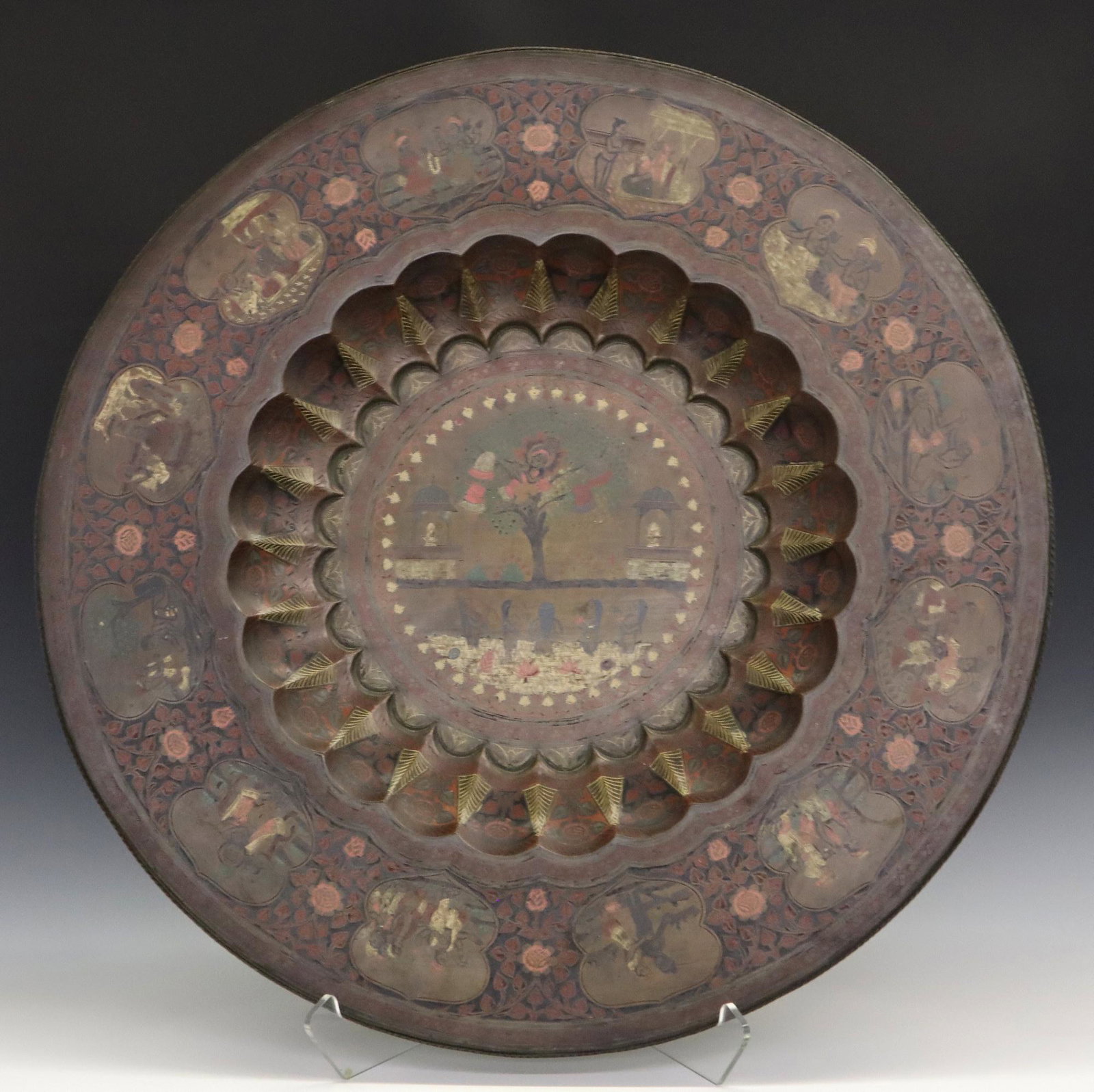 Indo-Persian Brass Charger: An Indo-Persian Brass Charger. Hammered Brass charger with engraved designs and a border containing multiple polychrome vignettes depicting figures in various pursuits, which surround a central scene 