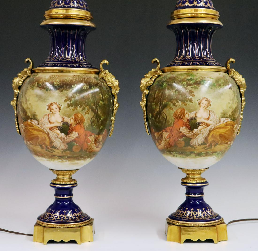 Pair of Bronze Mounted Table Lamps: A pair of 1940s bronze mounted porcelain table lamps. Hand painted and transfer decorated with gilt highlights. Marked "S. Bauchce, 1795" in decoration. Includes white fabric shades. Minor wear to dec
