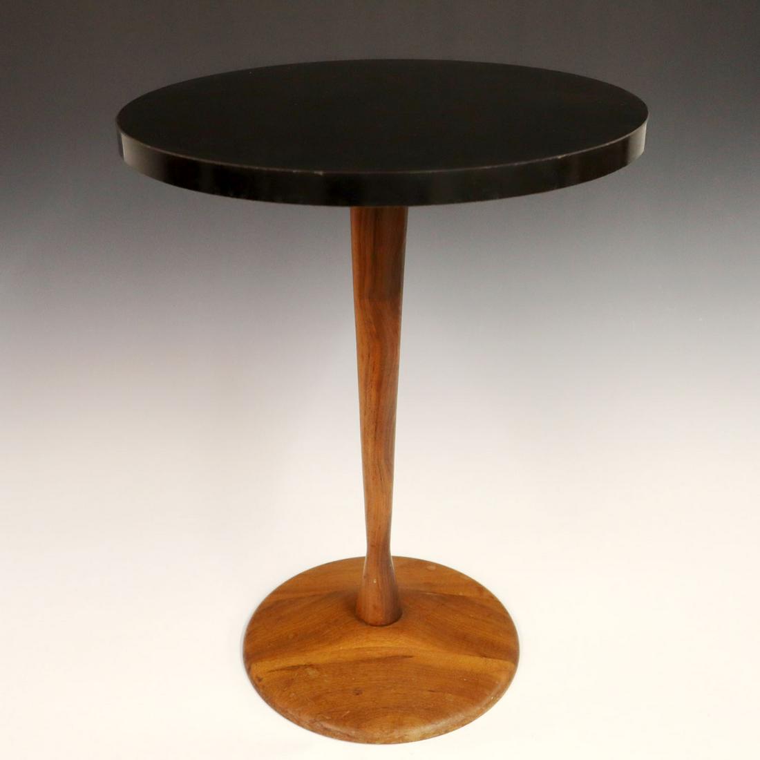 Teak Side Table: A mid-20th century teak side table. Round form with a black Formica top. Original finish on base with some minor scratches. Two small water stains and light scratch to the top, four small edge dings. 