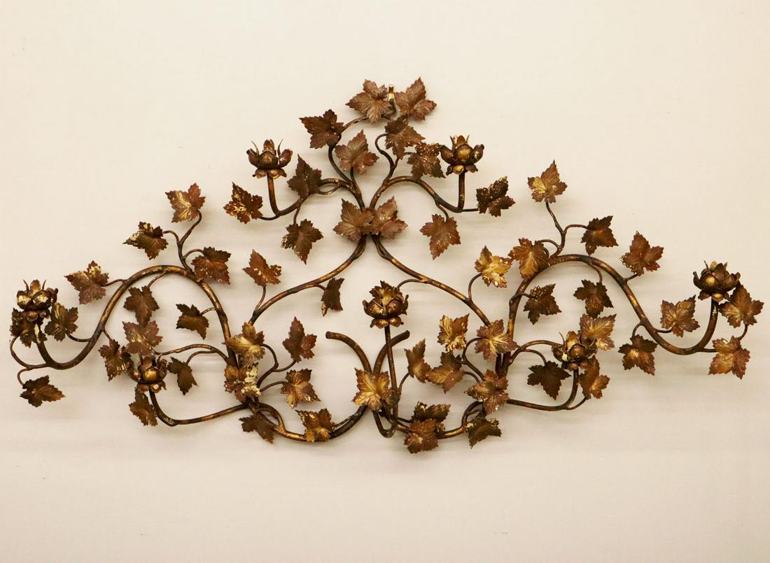 Wrought iron candle sconce: A 1920s Wrought Iron Candle Sconce. Having seven cups and ivy vine and leaf motif with gold paint overall. Some flaking to paint. 42 x 22" high. ESTIMATE $100-200