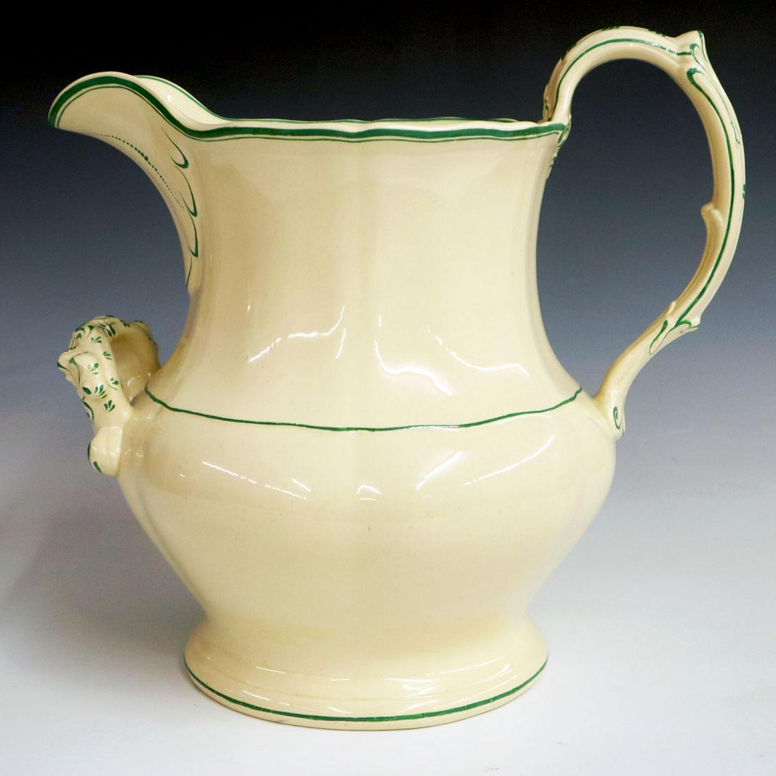 Ironstone Pitcher: A Mid-19th Century Ironstone Pitcher. Molded cream colored oversize pitcher with spout, front and rear handle decorated in green. Unmarked. Minor wear to green. 13 1/2 x 9 3/4 x 13" high. ESTIMATE $10