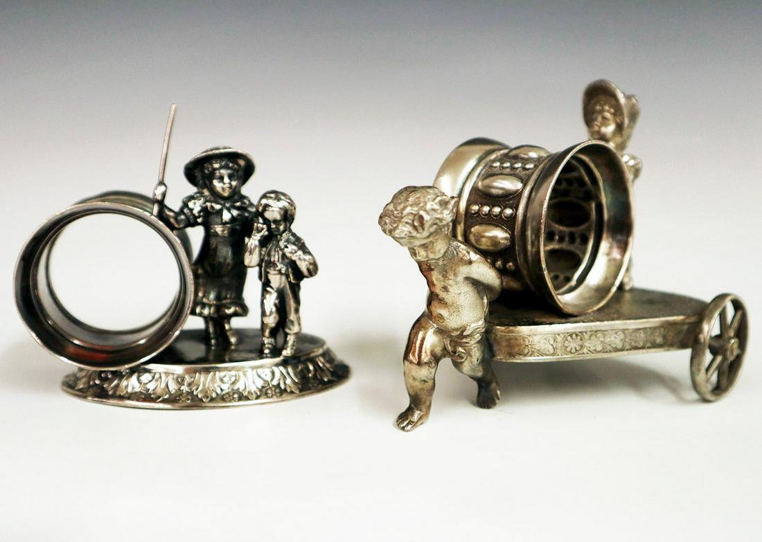 2 Silver Plate Napkin Rings: Two Early 20th Century Silver Plate Figural Napkin Rings. Including 1 by Smith & Bro. that depicts a Putto pulling a chariot with a little girl atop of it and 1 by Meridian Silver Plate Co. depicting