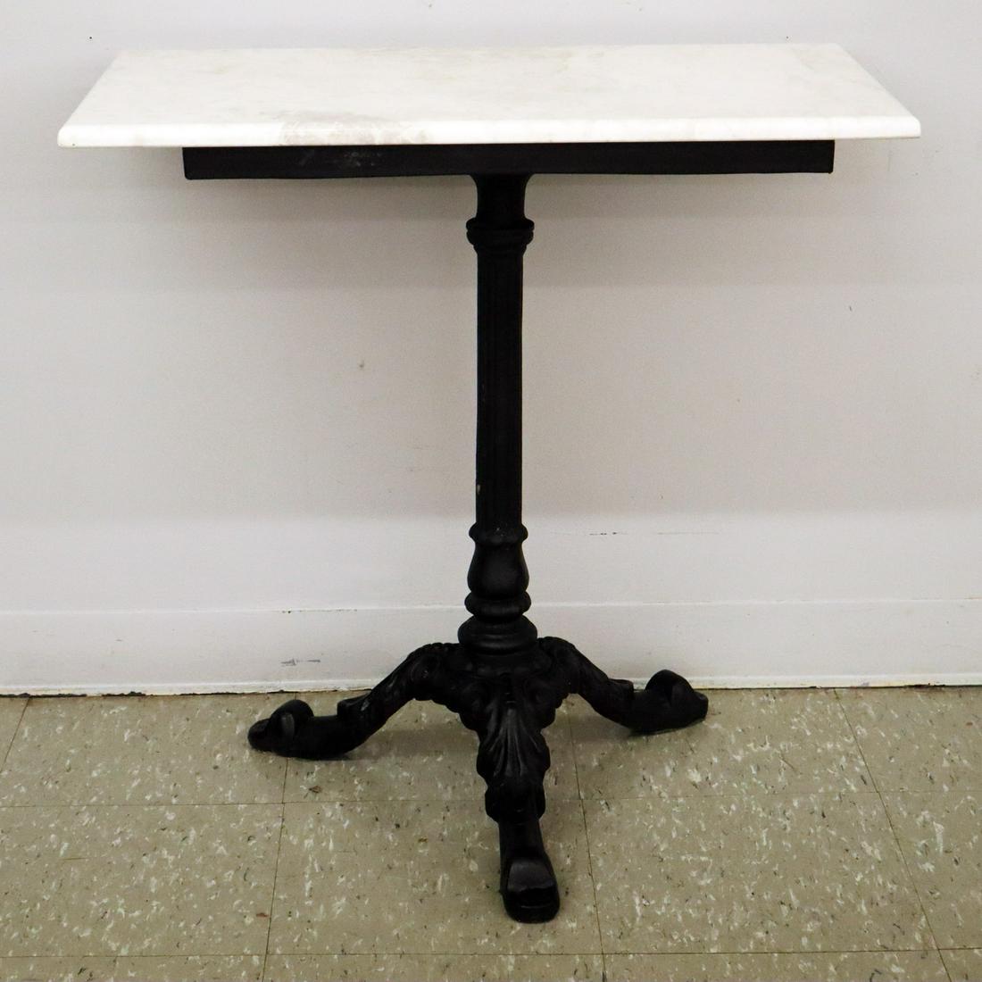 Cast Iron Cafe Table: A Late 19th Century Cast Iron Cafe Table. Having a fluted columnar center support that ends in a three leg base. Older repaint, replaced stone top. 24 x 16 1/2 x 29" high. ESTIMATE $200-300