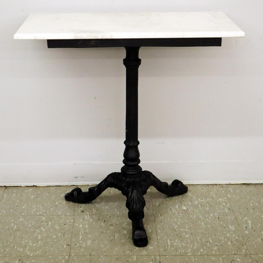 Cast Iron Cafe Table: A Late 19th Century Cast Iron Cafe Table. Having a fluted columnar center support that ends in a three leg base. Older repaint, replaced stone top. 24 x 19 1/4 x 29" high. ESTIMATE $200-300