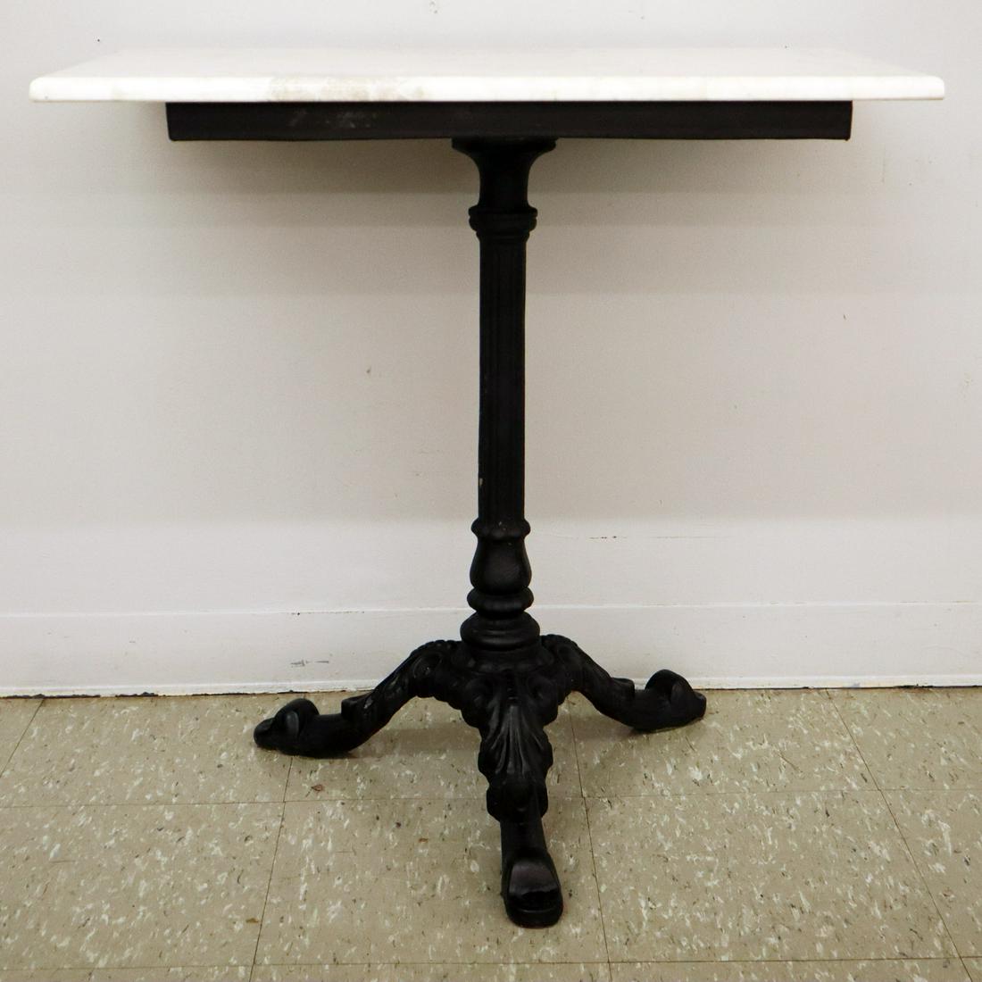 Cast Iron Cafe Table: A Late 19th Century Cast Iron Cafe Table. A Late 19th Century Cast Iron Cafe Table. Having a fluted columnar center support that ends in a three leg base. Older repaint, replaced stone top. 24 x 16 1/