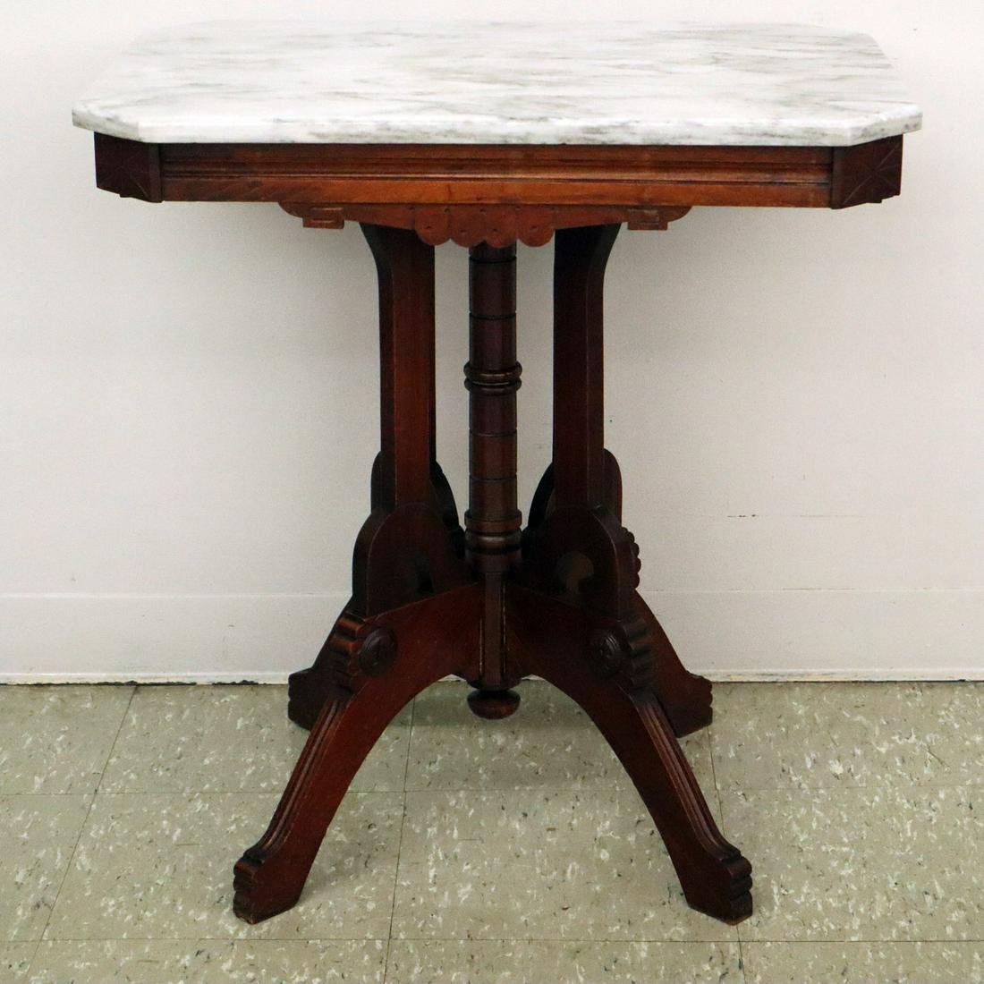 Parlor Table: A Mid 19th Century Eastlake Parlor Table. Walnut construction with original grey marble top that rests on a central column and four supports ending in four legs. Older refinishing with minor wear, lig