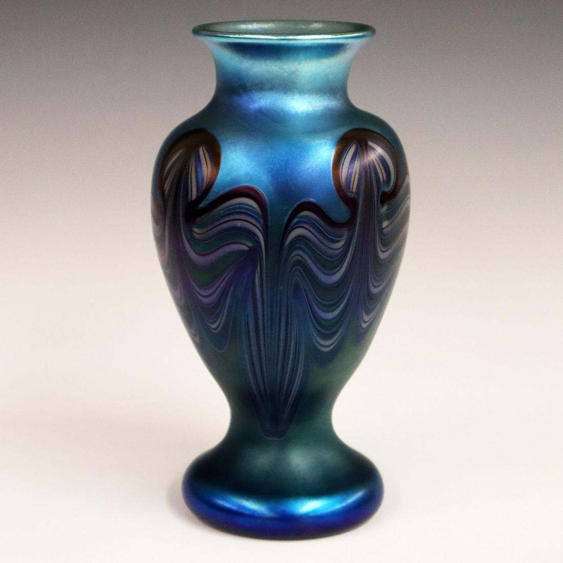 Orient & Flume Glass Vase: A Late 20th Century Orient & Flume Art Glass Vase. Having a pulled feather design in blue, green, and ivory amidst a blue iridescent ground. Etched mark of "Orient & Flume 1976 J 21" at the underside.