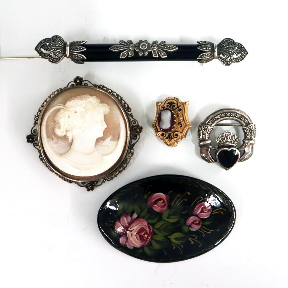 5 pcs Victorian & Edwardian Jewelry: Five pieces of Victorian & Edwardian Era Jewelry. Including 1 carved cameo brooch with filigree frame, 1 sterling and onyx bar pin, 1 sterling and onyx Claddagh brooch, 1 gold plated shield form brooc