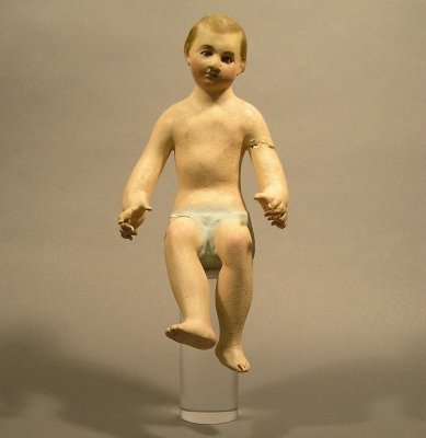 Santos: An early 20th century Spanish Colonial carved wooden Santos of the Christ Child. Original gesso and painted surface. Wear, flaking and older restoration. On a Lucite stand, 13 1/2" high, overall.