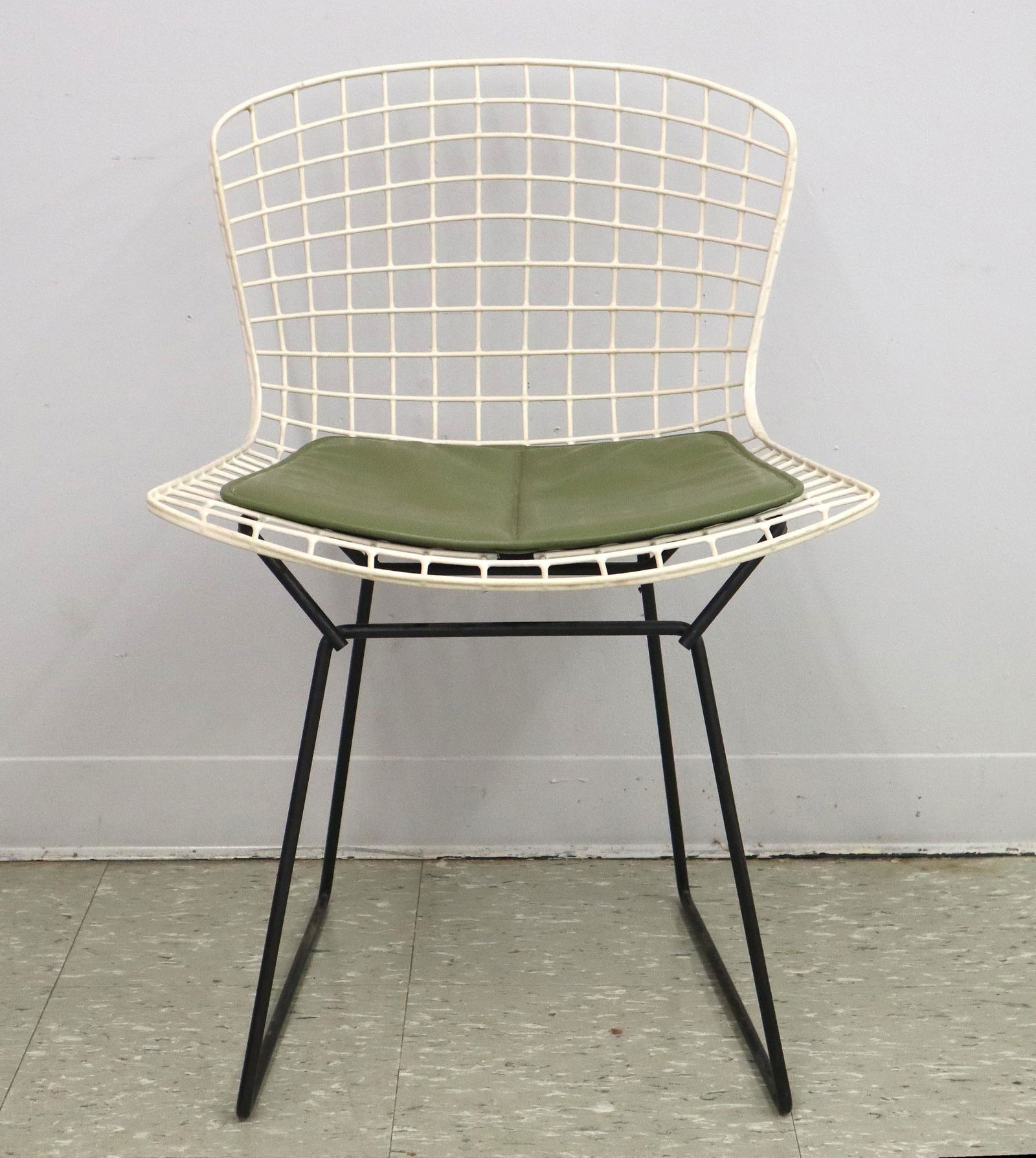 Henry Bertoia Wire Chair: A Henry Bertoia for Knoll Steel Wire Chair. White steel wire frame with green vinyl cushion and black legs. Cushion contains Knoll label; c. 1950's. Minor wear to white surface, foam in cushion is sti