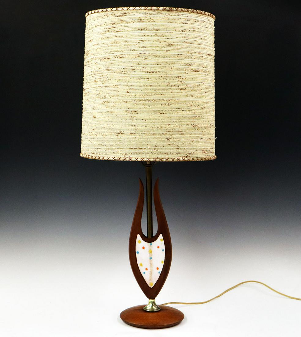 Mid-Century Table Lamp: A Mid-century Table Lamp. Walnut table lamp with a decorated enameled inlaid plaque, brass fittings, turned base, and a vintage thread decorated shade. Minor wear to finish, brass has some tarnish. 14