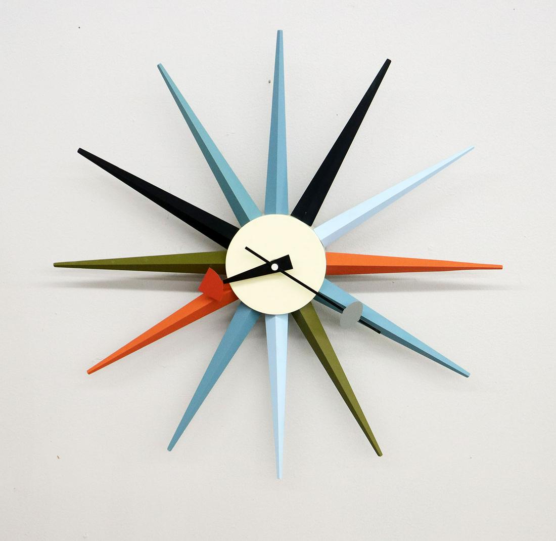 George Nelson Sunburst Clock: A Reproduction George Nelson style Sunburst Clock. -PLEASE NOTE -THIS IS NOT A VINTAGE CLOCK- Having 12 wooden "rays" radiating from a circular center, with multicolored decoration and quartz movement