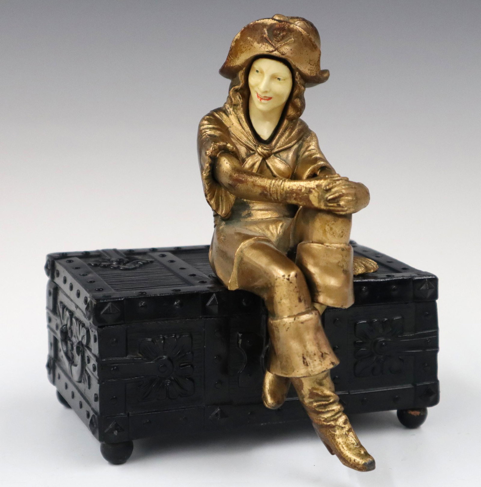1930's Musical Cigarette Box: A 1930's Cold Painted Musical Cigarette Box. Cold painted pirate figure with ivorine face sitting on a treasure chest, the music plays when the box lid is opened. Wear to the paint, hairlines on face.