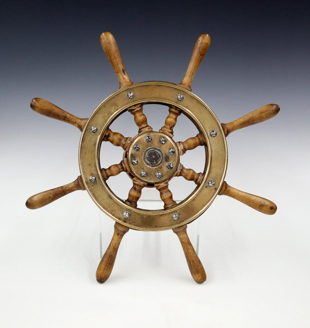 Yacht's Wheel: An early 20th century Yacht's Wheel. Having a brass inner hub and birch spokes with laminated brass outer wheel and a hardwood hub and iron shaft. Wear to the finish. 15" diameter. ESTIMATE $100-200