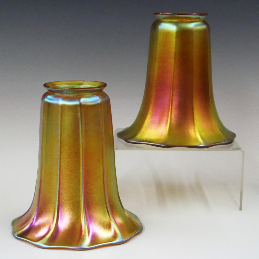 2 Steuben Art Glass Lamp Shades: Two Steuben Gold Aurene Art Glass Lamp Shades. Each is of ribbed bell form with 2 1/4" fitters. One with partial acid etched mark. One has a small chip on the fitter rim, slight wear at the base. 4 3/