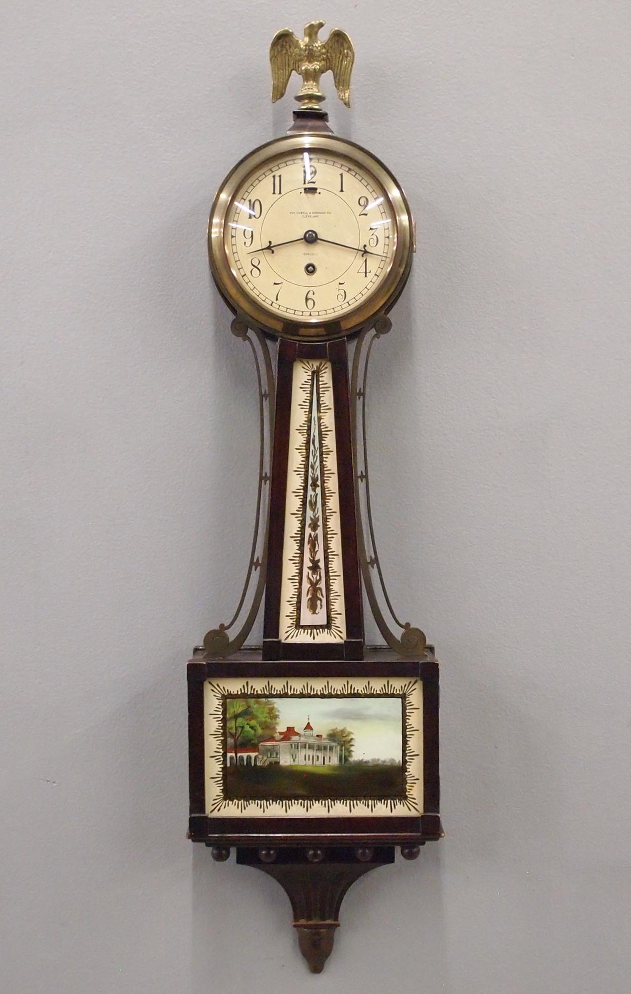 Chelsea Banjo Clock: An early 20th century Chelsea Banjo clock retailed by "The Cowell & Hubbard Co., Cleveland". 8-day spring driven time only movement with painted metal dial Mahogany case with Brass arms and Eagle fini