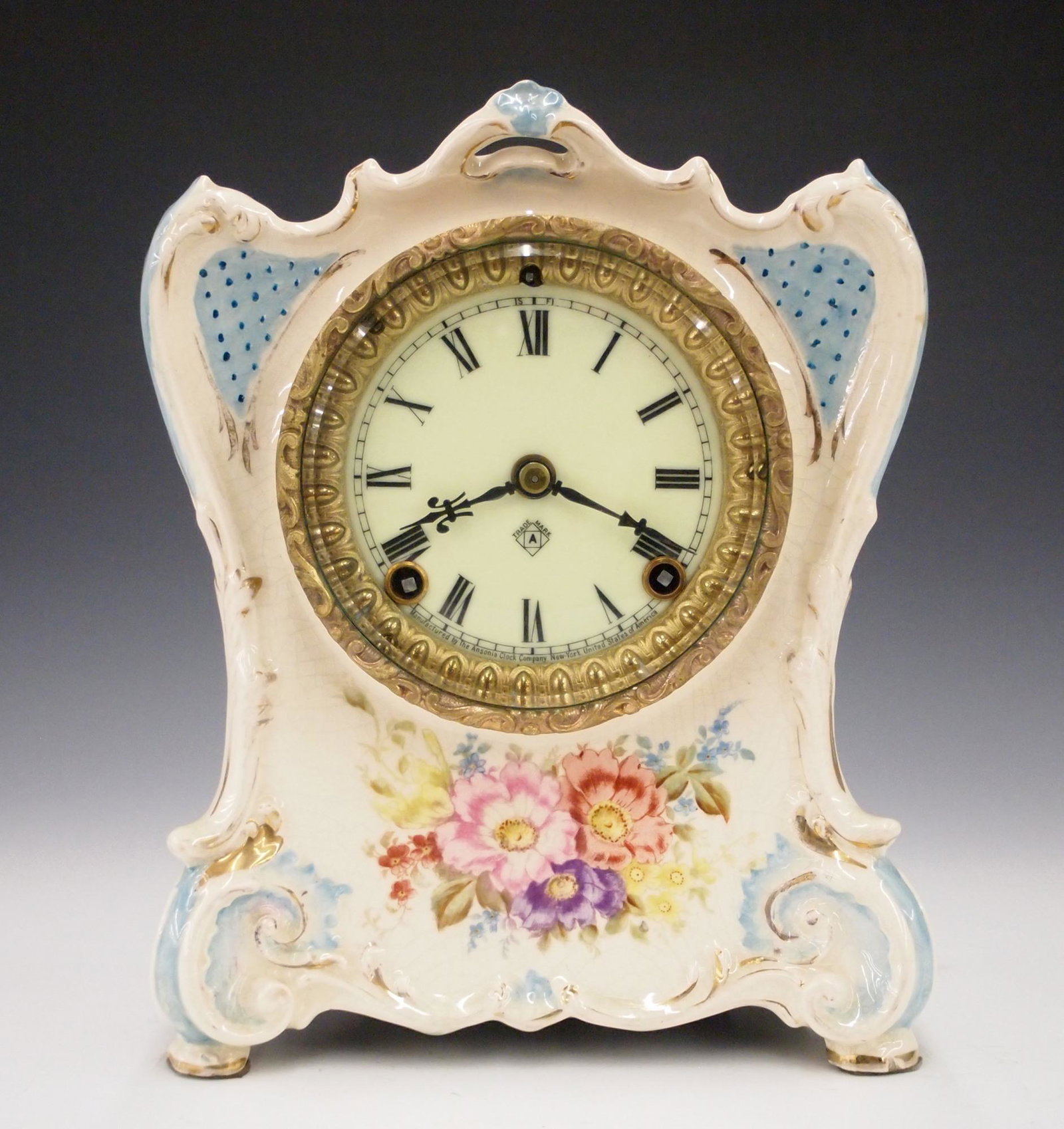 Ansonia La Charite China Shelf Clock: A turn of the century Ansonia "La Charite" model china shelf clock. 8-day time and strike movement with porcelain dial and Roman numerals. Royal Bonn porcelain case with floral decoration. Some wear, 