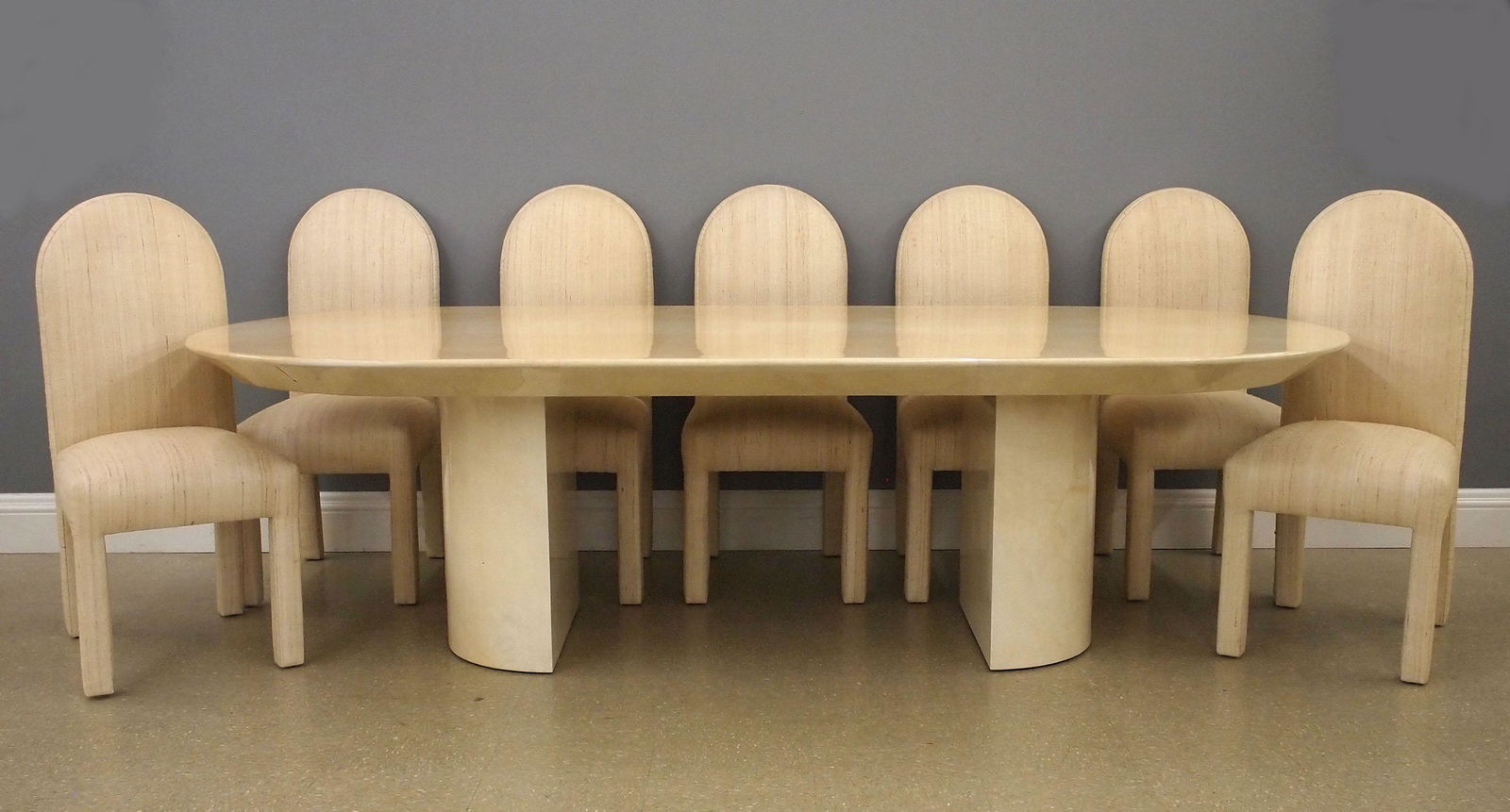Karl Springer 11 pc Dining Set: A 1970's Karl Springer dining set in lacquered Parchment. Includes an oval "Knife Edge" dining table with twin pedestal base and ten high back dining chairs with arched backs and dupioni silk upholste