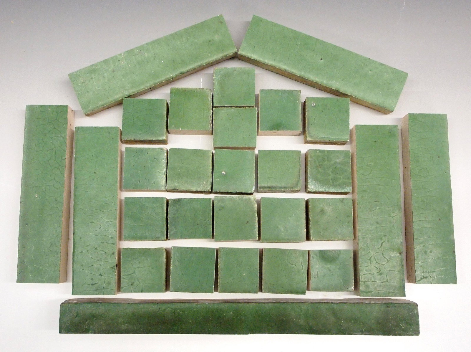 73 Grueby Border Tiles: A collection of seventy-three Grueby border tiles. Includes one large rectangular tile, twenty four medium sized rectangular tiles, and forty eight small square tiles; all in a matte Green glaze. Unma